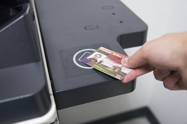 Picture of hand holding ID card against to the detector - top right surface of printer/copier